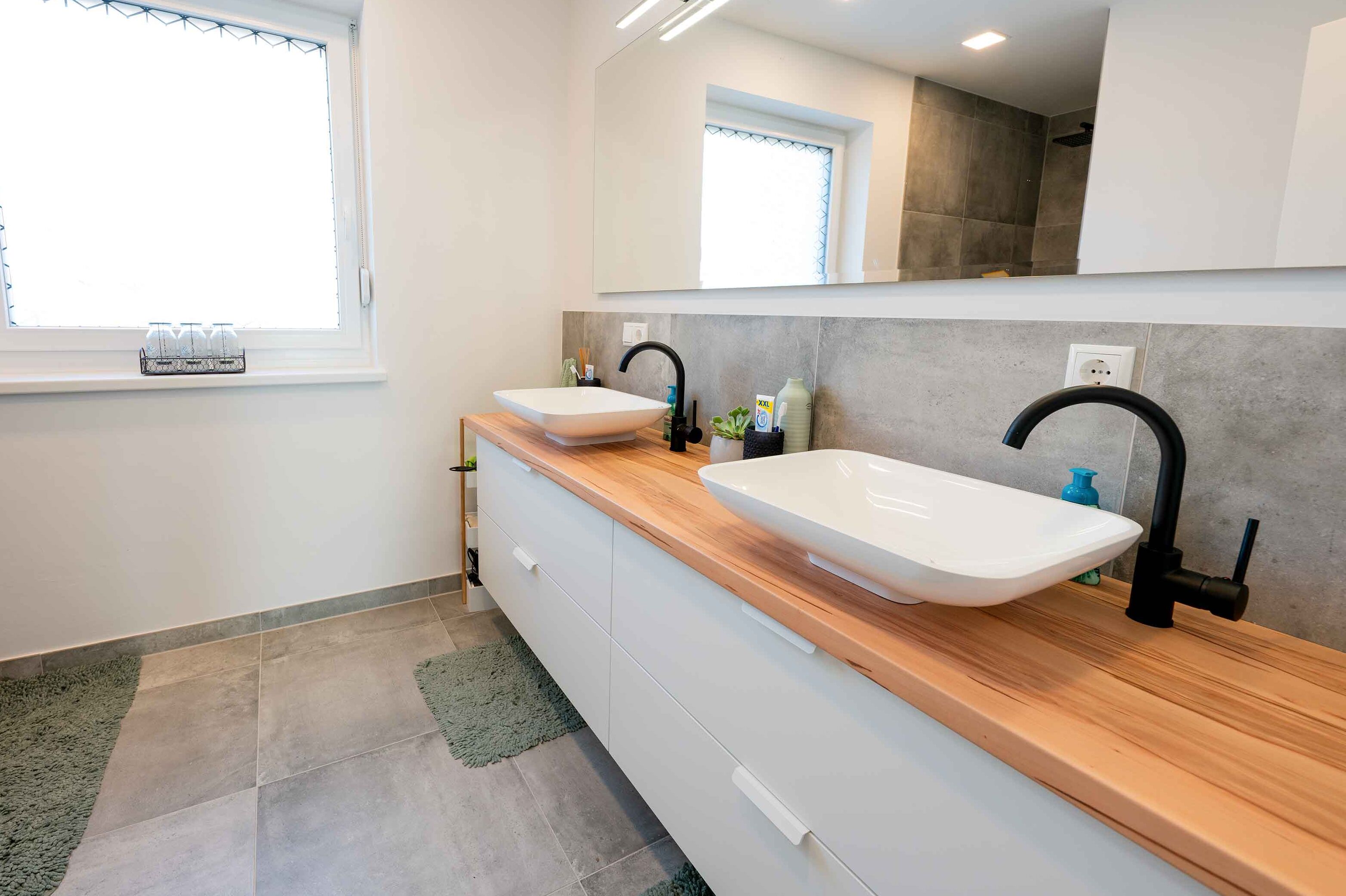 Bild zeigt Badezimmer mit grauen Fließen und modernem Doppelwaschtisch.