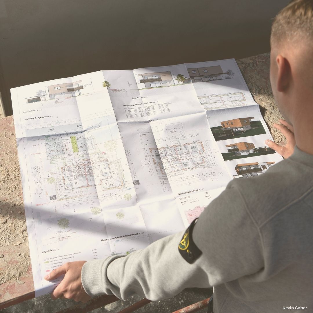 Bild zeigt Mathias Kölbl von hinten auf einen Bauplan schauend.